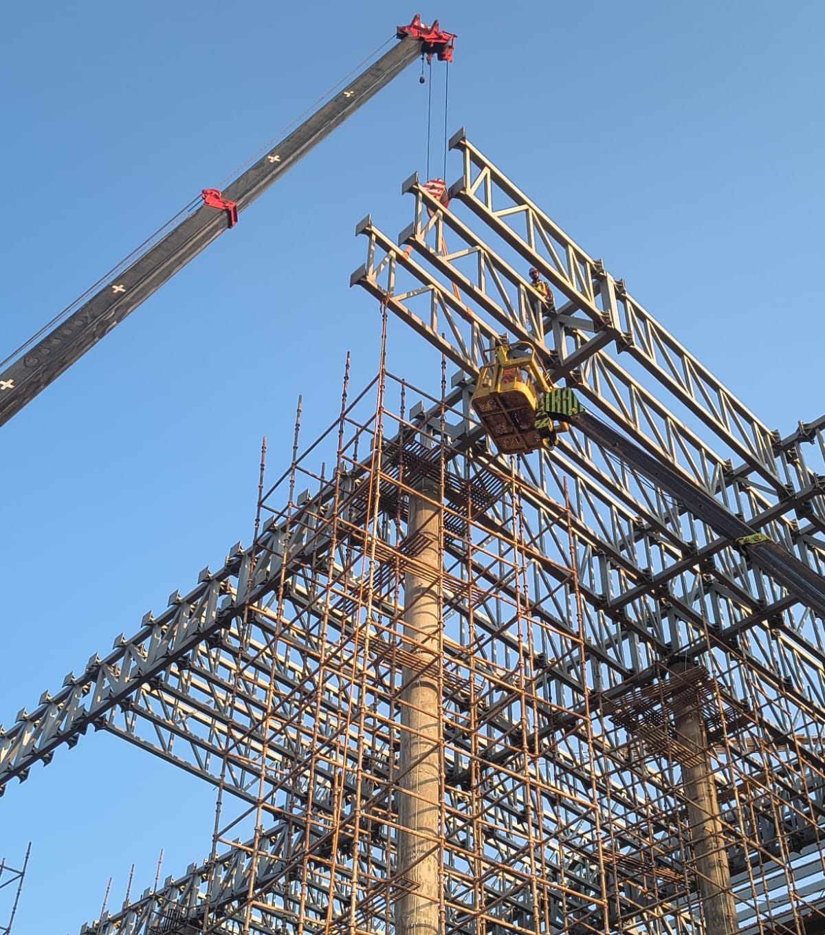 Truss being landed by mobile crane over a scaffolded frame